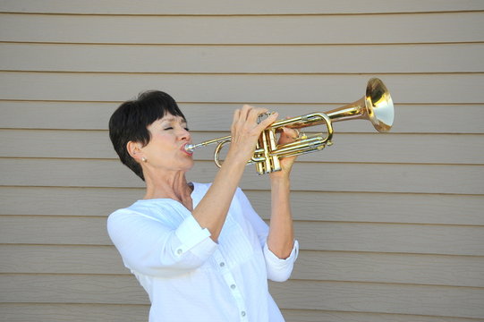 Female beauty blowing her trumpet loudly outside.