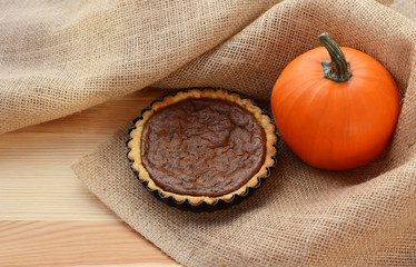 Fototapeta na wymiar Pumpkin pie and pumpkin in hessian