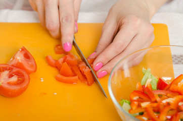 Close up of a female hand cutting tomatoes for cooking vegetable salad