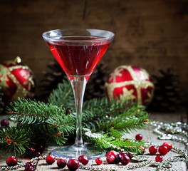 Red Christmas cocktail in a martini glass with fir branches, pin