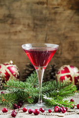 Red Christmas cocktail in a martini glass with fir branches, pin