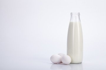Old glass bottle with milk and eggs on white background.