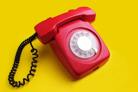 Red retro telephone on yellow background