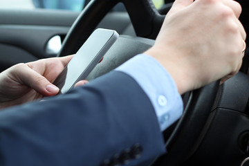 The businessman using mobile smart phone while driving the car
