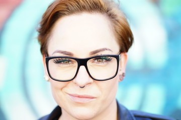 Pfiffige Frau mit heller, reiner Haut und kurzem Haar, die eine schwarze, moderne Brille trägt und...