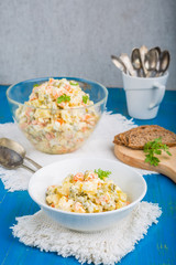 Salad olivier in bowl on blue table. Russian traditional salad.