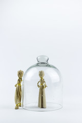Man and woman straw dolls, separated by a glass bell