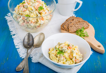Salad olivier in bowl on blue table. Russian traditional salad.