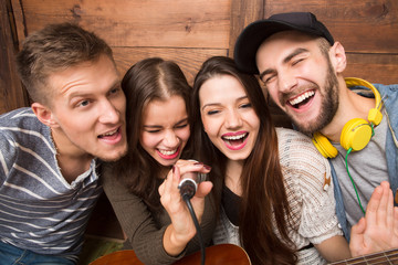 Happy friends spending their free time singing karaoke