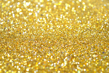 Blurred holiday background with golden glitter sparkles with place for your text