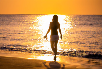 Woman on the beach in Bali Indonesia holding her sandals