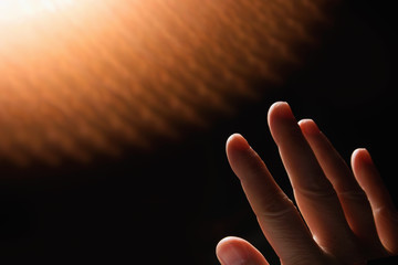 A male human hand reaches out to feel radiating heat.