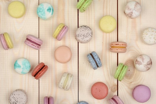 A lot of multicolored macarons on wooden background