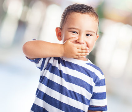 portrait of a cute kid covering his mouth with his hand