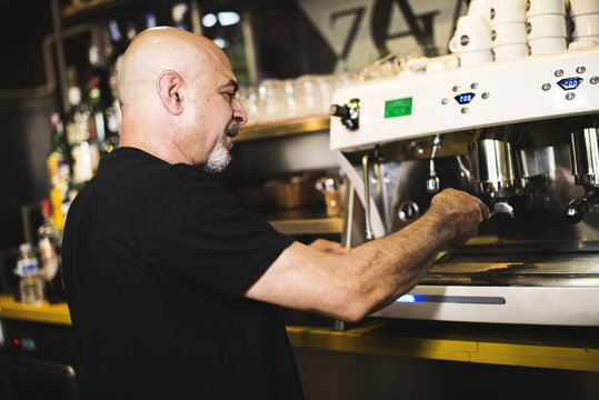 Hombre prepara suculento cafe en un bar. Gente real.