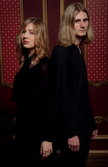 Couple of young blond people dressed in black in a dark room
