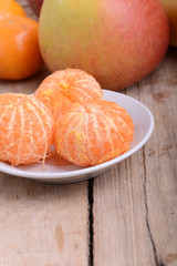 Bowls of slices mandarin with apple on rustic wooden background