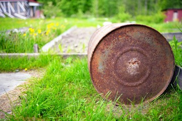 Old rusty barrel against a green grass