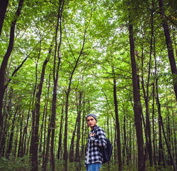 Naklejka na ściany i meble Portrait of young handsome man with backpack wanderer walk in the woods