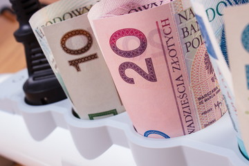 Rolls of polish currency money in electrical power strip with connected plug, energy costs
