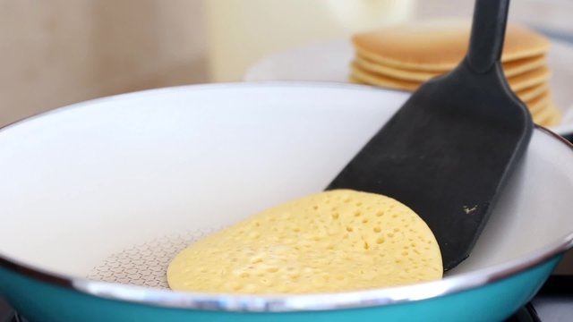 Making home made pancakes on frying pan. Turning over flapjacks
