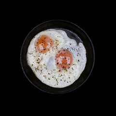 Scrambled eggs in iron skillet, top view isolated black