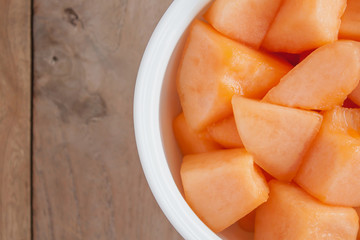 closeup melon slice in white dish with wood table background