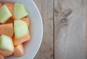 closeup melon slice in white dish with wood table background