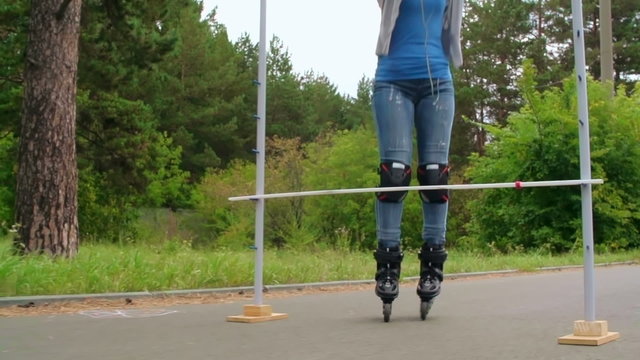 Female inline skater jumping over a bar in slow-mo 