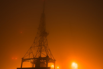 Communication tower in fog over hill