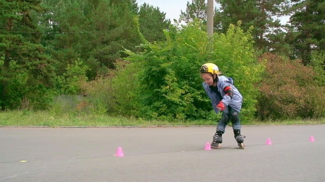 Cute little inline skater learning to skate between cones 