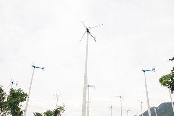 Wind turbine on the green grass over the blue clouded sky
