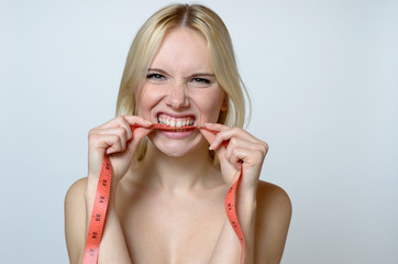 Bare Young Woman Biting a Measuring Tape