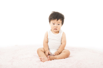 じゅうたんに座る肌着姿の赤ちゃん