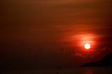 sun disk among red sky fishing boats on horizon at sunrise