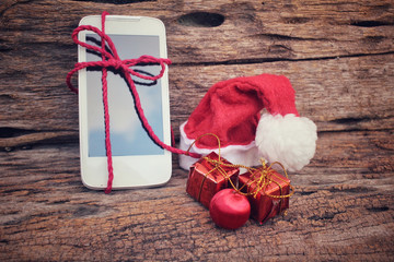 Obraz na płótnie Canvas Smart phone and gift with christmas hat