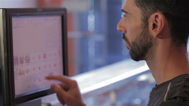 Man at cash register typing on the touchscreen