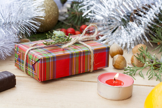 Christmas gift box and red candle with New Year's and Christmas decoration midst fruits and tinsel