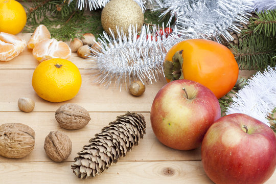 Apples in Christmas decor with Christmas tree, nuts and apples on light wooden background