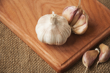 Garlic on cutting board , close-up on sacking. burlap background