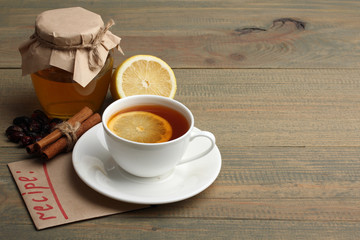 a Cup of tea with lemon and a jar of honey near a pile of drugs on wooden background