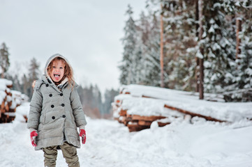 Fototapeta na wymiar child girl playing with snow in winter walk in forest, outdoor activities