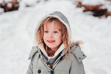 child girl playing on cozy snowy forest walk, outdoor winter activities