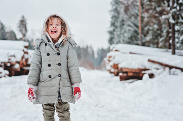 child girl playing on cozy snowy forest walk, outdoor winter activities