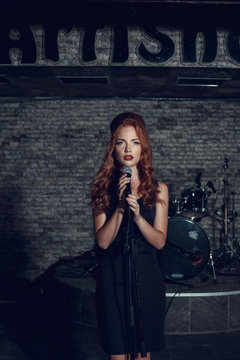 Young singer woman with red hair on the scene