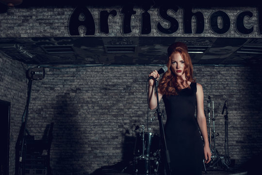 Young singer woman with red hair on the scene