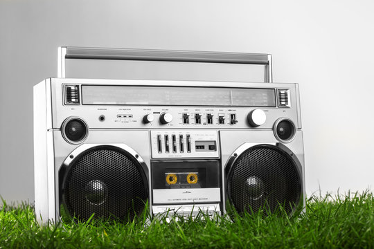 Retro-styled silver boom box over green grass isolated