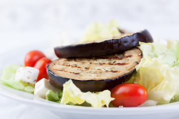Salad with grilled eggplants, tomatoes, feta cheese and lettuce. Closeup