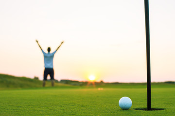 Happy golf player on a golf court at sunset