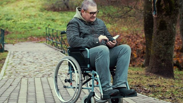 Disabled man using tablet PC in wheelchair